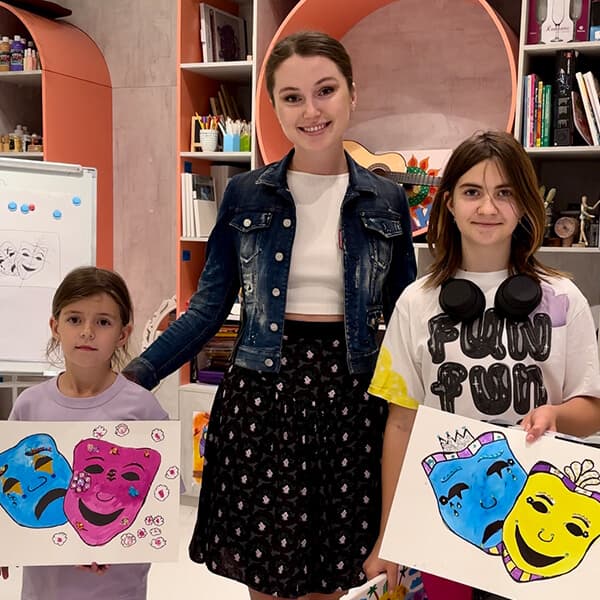Inga Chalaia with a guest holding painted theatre masks at a celebration in Dubai